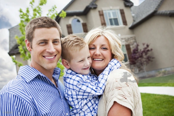 A young family standing in front of their new home