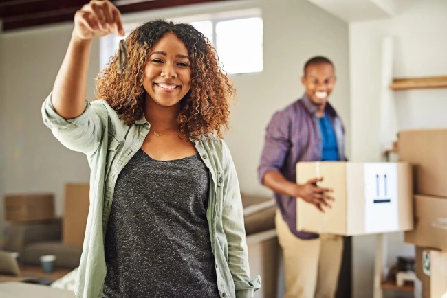 Happy couple celebrating in their new home with moving boxes, representing successful homeownership achievement