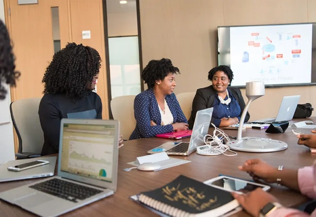 Professional credit counseling session with three women reviewing financial documents at a modern conference table